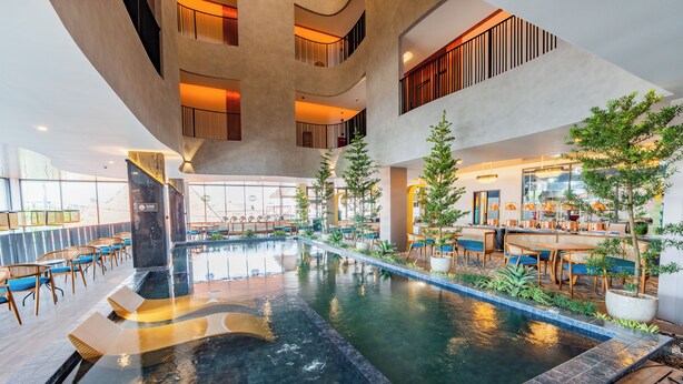 Un espace piscine intérieur moderne, doté de sièges et d’un bar.