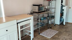 A kitchen with a microwave, coffee maker, and shelves with dishes. - Peaceful spacious studio in Vista surrounded by greenery and birdsong. (Vista)