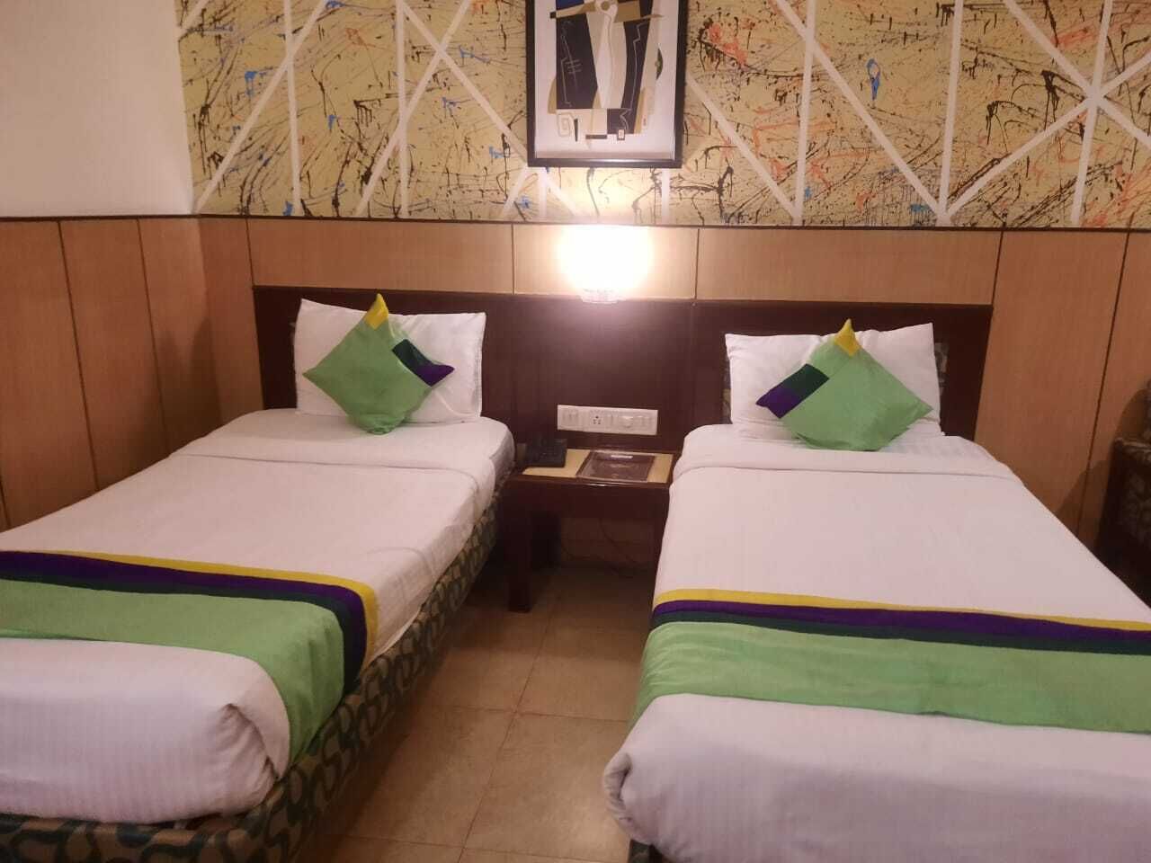 Two single beds with green and purple accents, a wooden headboard, a nightstand, and a map on the wall.