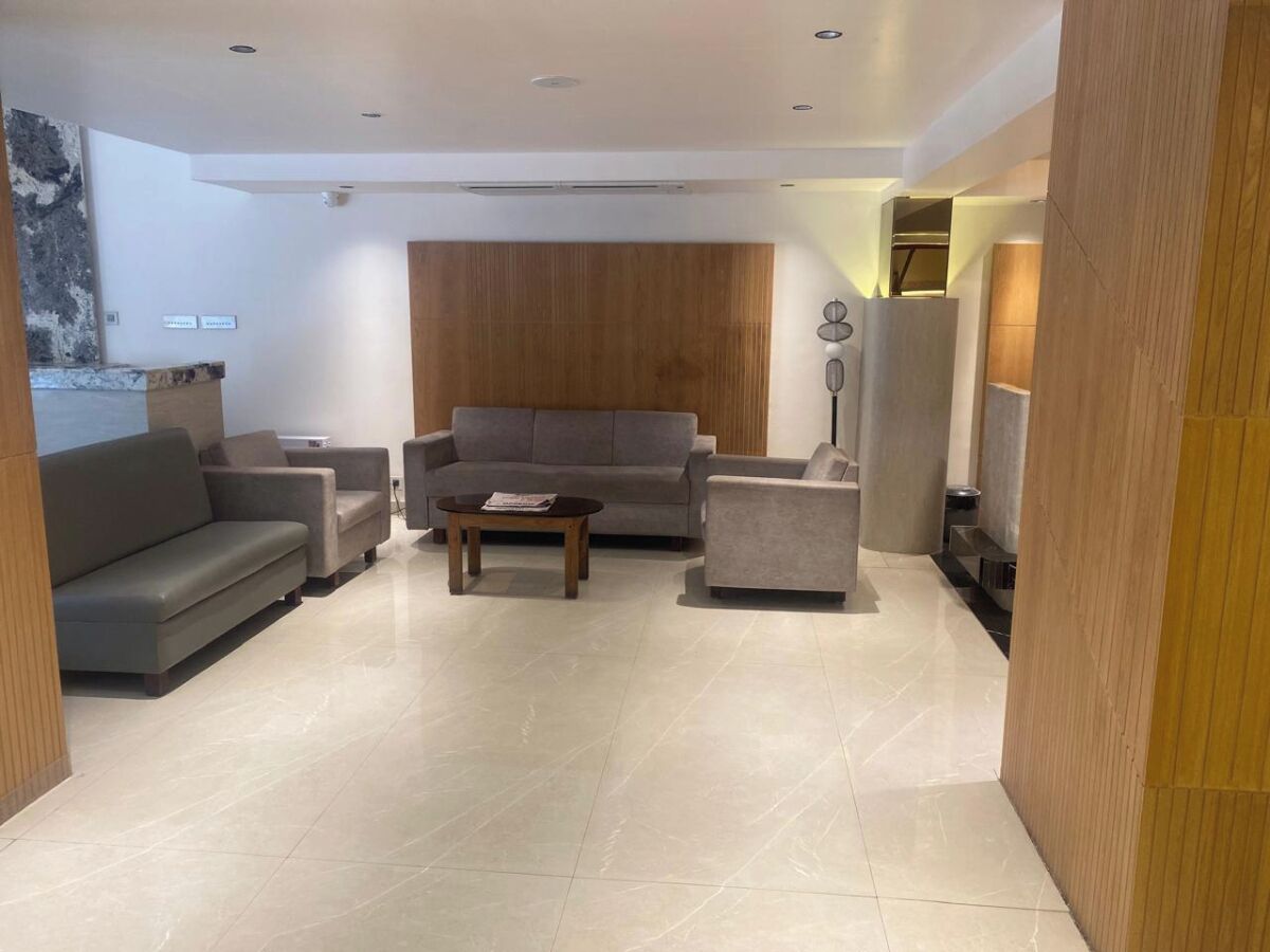 A modern living room with a grey sofa, a coffee table, and a wooden accent wall.