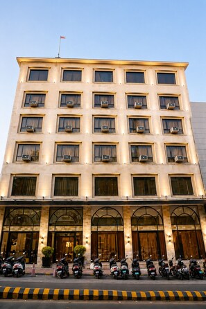 Ein mehrstöckiges Hotel mit einheitlicher Fassade, Klimaanlagen in jedem Fenster und einer Reihe geparkter Roller davor.