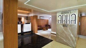 A modern hotel lobby with a reception desk, seating area, and a marble wall with the hotel's name. - Konaark's Arka Hotels Nagpur  (Nagpur)