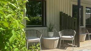 Een overdekt terras met rieten stoelen en een potplant.