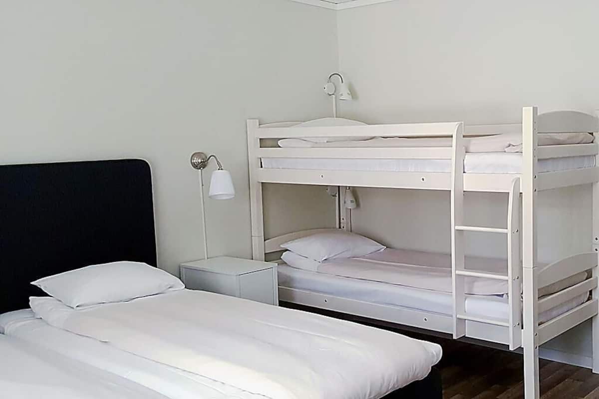 A bunk bed room with a desk and lamp.