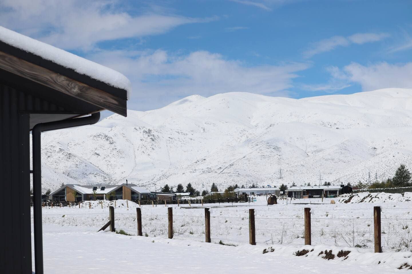 A snow-covered landscape with a mountain in the background and a building with a sloped roof in the foreground.