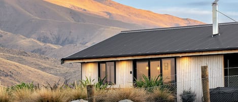 A modern house with a metal roof, large windows, and a view of mountains.