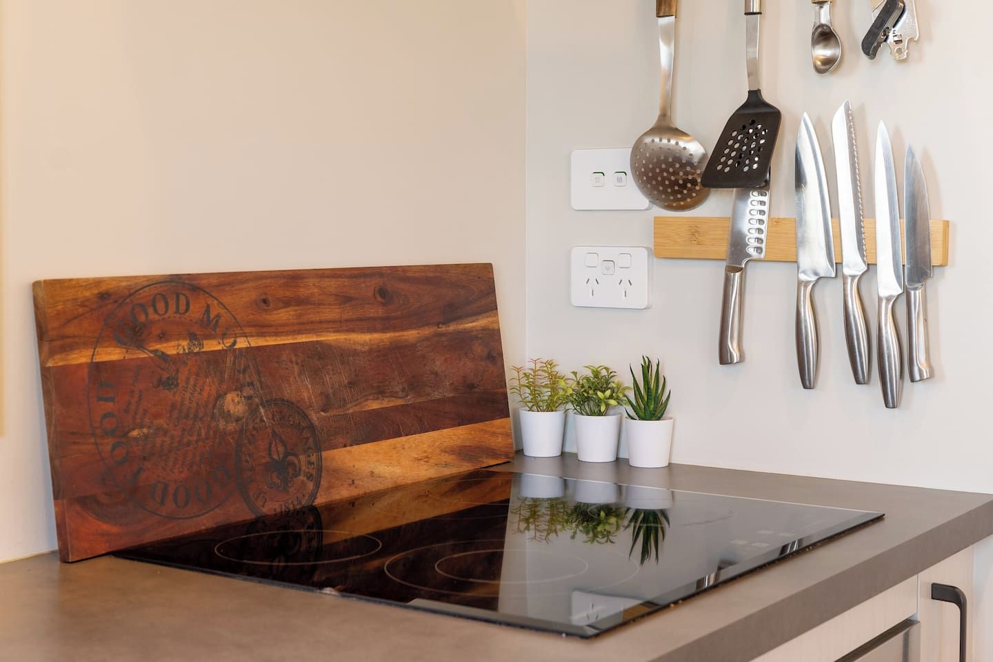 A kitchen with a wooden backsplash, a built-in stove, and various utensils hanging on the wall.