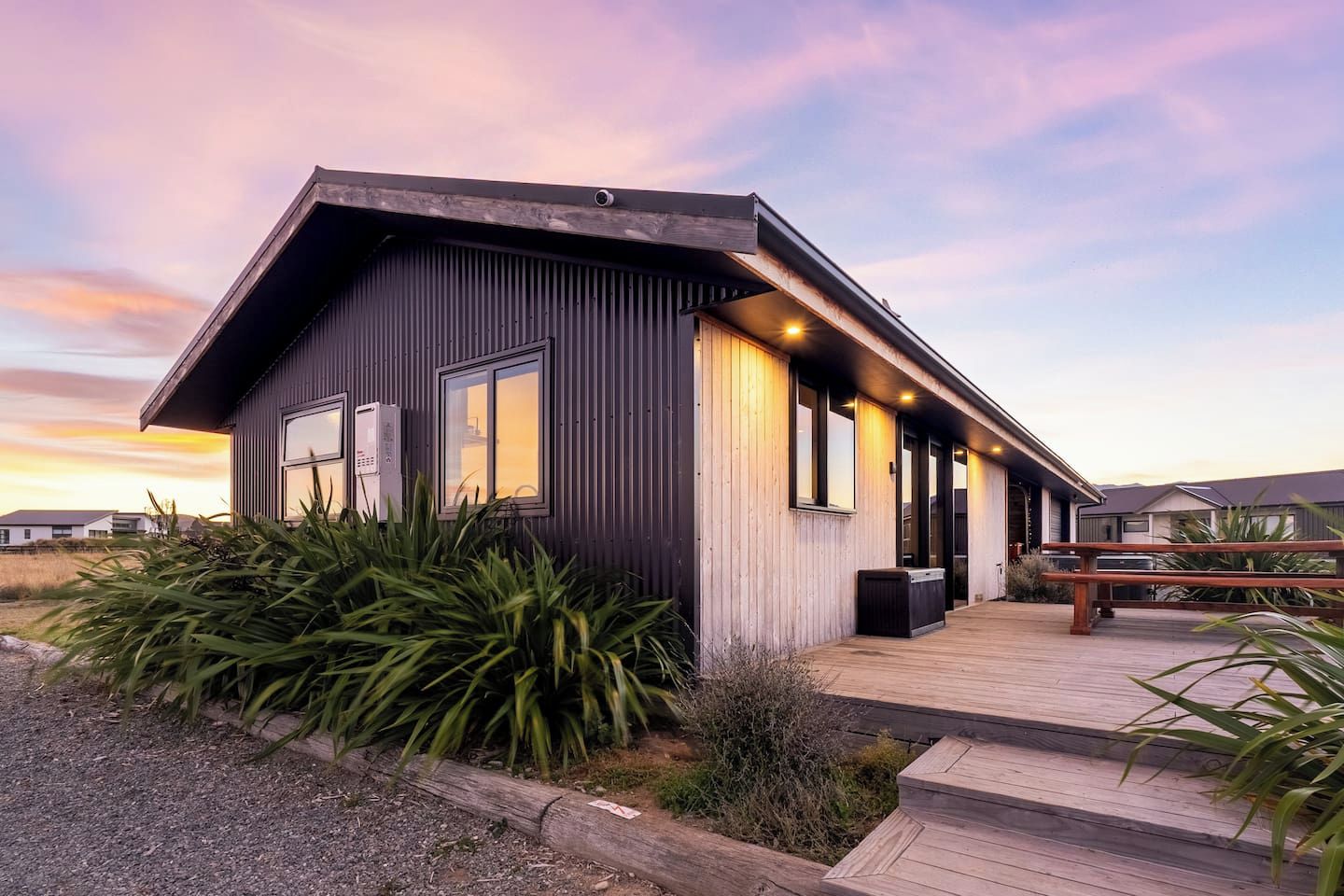 A modern building with a flat roof, large windows, and a wooden deck.