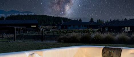 Un jacuzzi con vista a la Vía Láctea, rodeado de casas y una zona delimitada por una cerca.