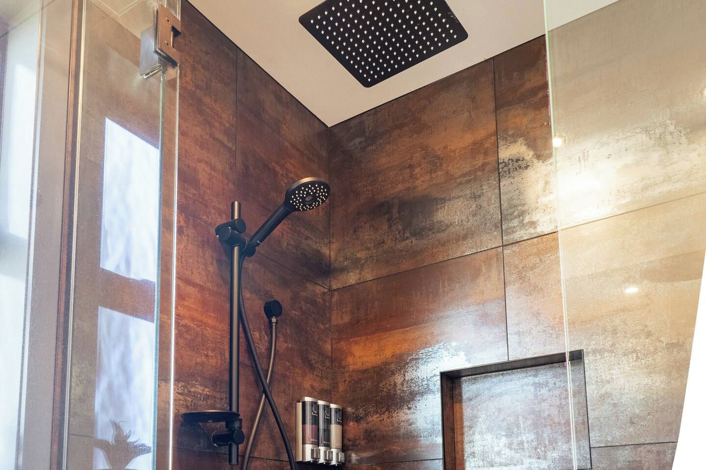 A modern shower with a handheld showerhead and a wall-mounted rain showerhead.