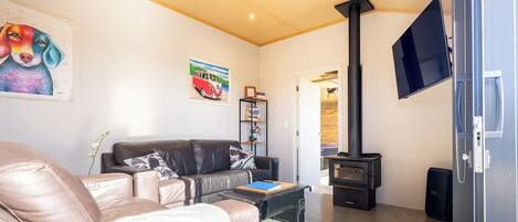 A living room with a sofa, a flat-screen TV, a fireplace, and a bookshelf.
