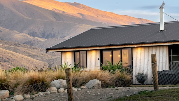 Una casa moderna con tetto in metallo, ampie finestre e vista sulle montagne.
