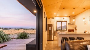 Una cucina moderna con frigorifero in acciaio inossidabile, soffitto in legno e sgabelli da bar.