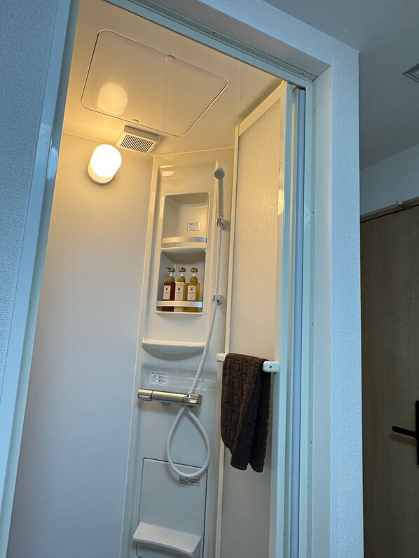 A shower with a towel rack and a shelf with toiletries.