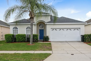 A single-story house with a blue front door, a garage, and a well-maintained lawn. - Four Bedrooms, 3 Baths, No Rear Neighbors,  Just Minutes walk  to Clubhouse (Kissimmee)