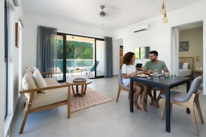 A modern living room with a sofa, dining table, and chairs. There is a balcony with outdoor furniture. - Bo Jungle - Steps to Tamarindo Beach - Surf & Pool #4 (Playa Langosta)