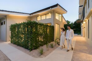 A modern house with a covered outdoor area, a pathway, and a hedge. - Casa Bo Jungle - Steps to Tamarindo Beach - Surf & Pool (Playa Langosta)