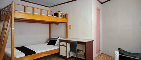 A bunk bed with a desk and chair, a small cabinet, and a pink door.