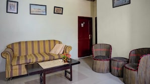 A room with a striped sofa, a small table with a vase, and patterned chairs. - Hotel O near Monument Historique Berasta (Berastagi)