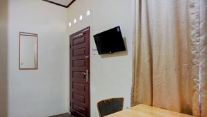 A room with a wooden door, a television mounted on the wall, a table, and a chair. - Hotel O near Monument Historique Berasta (Berastagi)