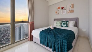 Un dormitorio con un ventanal grande, una cama con manta color turquesa y tres obras de arte en la pared.
