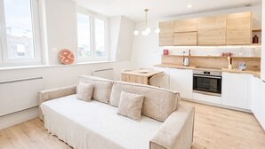 Une cuisine moderne avec des meubles en bois, un four encastré et un coin repas comprenant une table et des chaises.