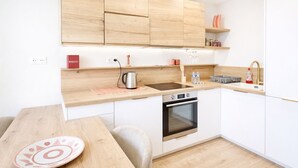 Une cuisine moderne avec des meubles en bois, un four encastré, un évier et un coin repas comprenant une table et des chaises.