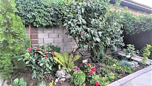 Un jardin agrémenté de diverses plantes et fleurs, un mur en briques et une clôture en bois.