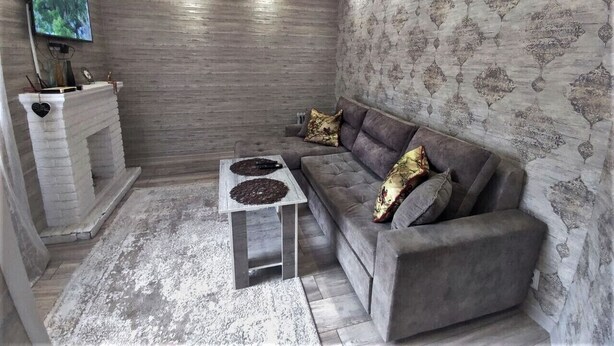 Un salon moderne avec un canapé gris, une table basse blanche, une cheminée et un papier peint à motifs.