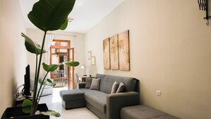 Ein modernes Wohnzimmer mit einem Ecksofa, einer Topfpflanze und Kunstwerken an der Wand.
