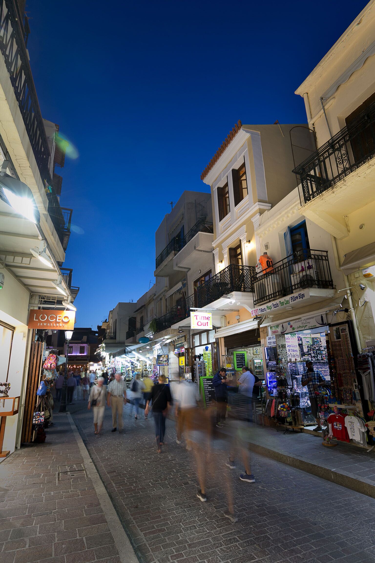A bustling street scene at dusk with shops and pedestrians.