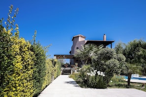 Ein modernes Gebäude mit Pool, umgeben von üppigem Grün und blauem Himmel.