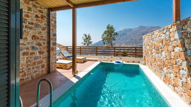 A pool area with stone walls, wooden deck, and a view of mountains. - Beautiful sea views, Close to Beautiful Beaches of South Crete (Rethymno)