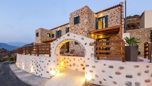 Un bâtiment en pierre avec une porte en bois, un balcon et une vue sur les montagnes.