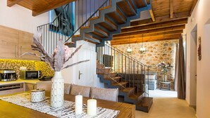 Une cuisine moderne avec un coin repas, un escalier et un mur en pierre.