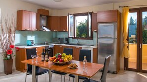 Eine moderne Küche mit Holzschränken, einem Edelstahlkühlschrank, einem Esstisch mit Stühlen und einer Obstschale.