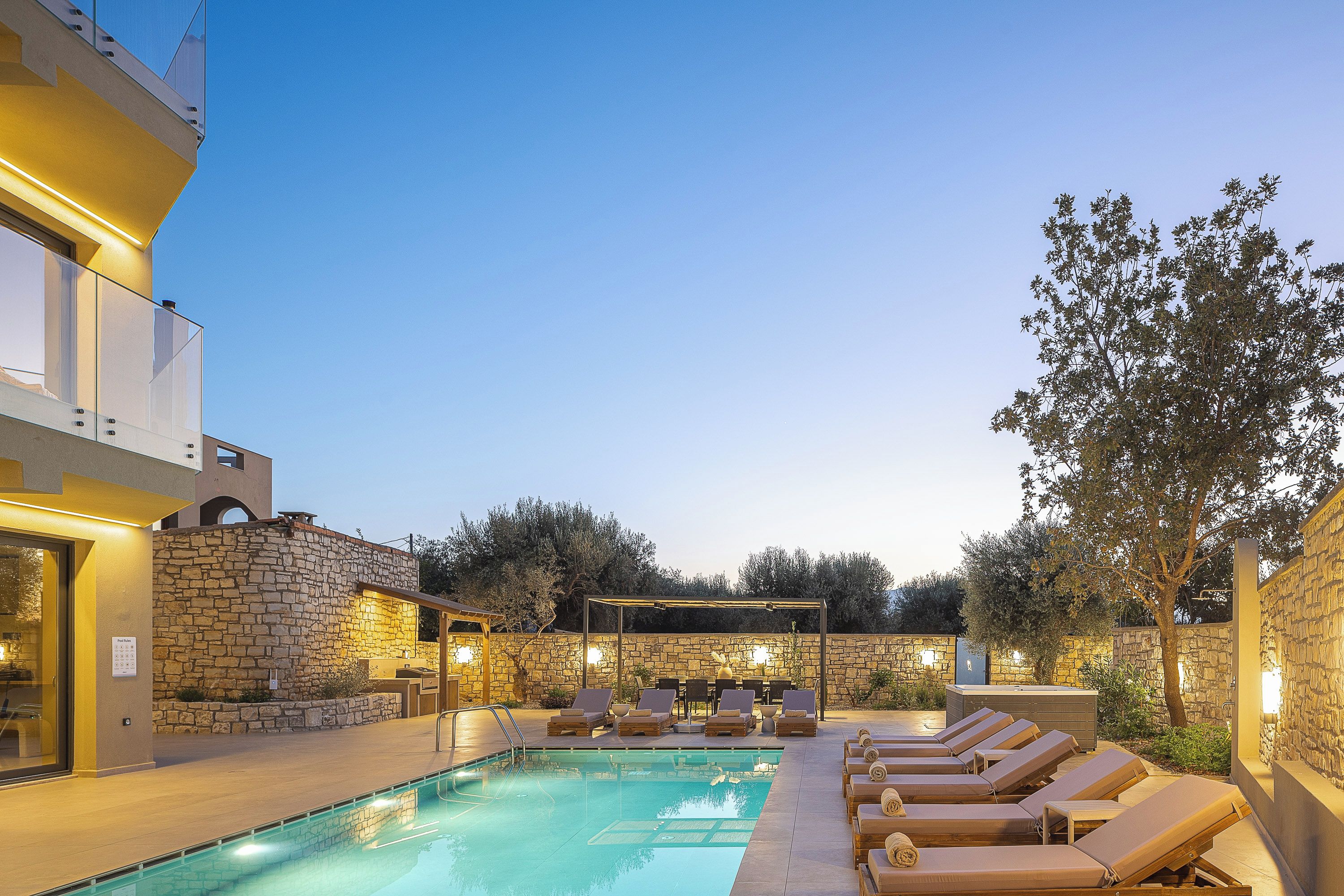 A swimming pool with lounge chairs and a stone wall.