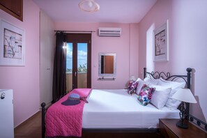 Ein Schlafzimmer mit einem Bett, einem Nachttisch, einer Lampe, einer Klimaanlage, einem Spiegel und einem Fenster mit Vorhängen.