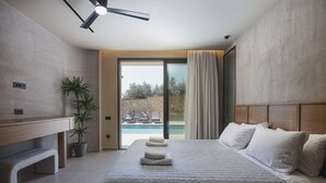 Ett hotellrum med en säng, en takfläkt, en krukväxt, utsikt över en pool och en vägg av sten.