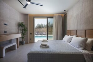 Ein Hotelzimmer mit einem Bett, einem Deckenventilator, einer Zimmerpflanze, Blick auf einen Pool und einer Steinwand.