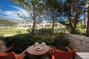 Eine Terrasse mit einem runden Tisch, zwei Stühlen, einer Toastplatte und zwei Tassen.