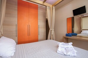 Ein Hotelzimmer mit einem Bett, einem Holzschrank, einem Spiegel und einem Fernseher.