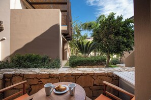 A patio with a table set for two, overlooking a garden with various plants and a clear blue sky. - A & C Home 2: Two Bedroom Apartment 100m from Plakias Beach sandy beach (Rethymno)