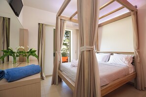 A bedroom with a canopy bed, a flat-screen TV, and a view of the outdoors. - A & C Home 2: Two Bedroom Apartment 100m from Plakias Beach sandy beach (Rethymno)