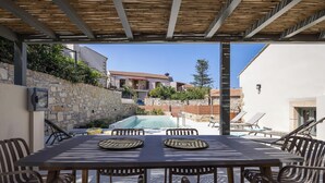 En udendørs terrasse med pool, stenvægge og udsigt til en bygning i baggrunden.