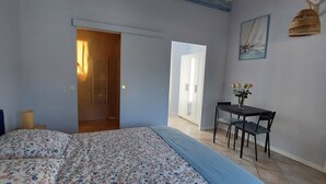 A bedroom with a bed, a desk, and a chair. There is a door leading to another room. - Bed and breakfast, Besse sur Issole, Var. Ideal for a quiet, sunny stay (Besse-sur-Issole)