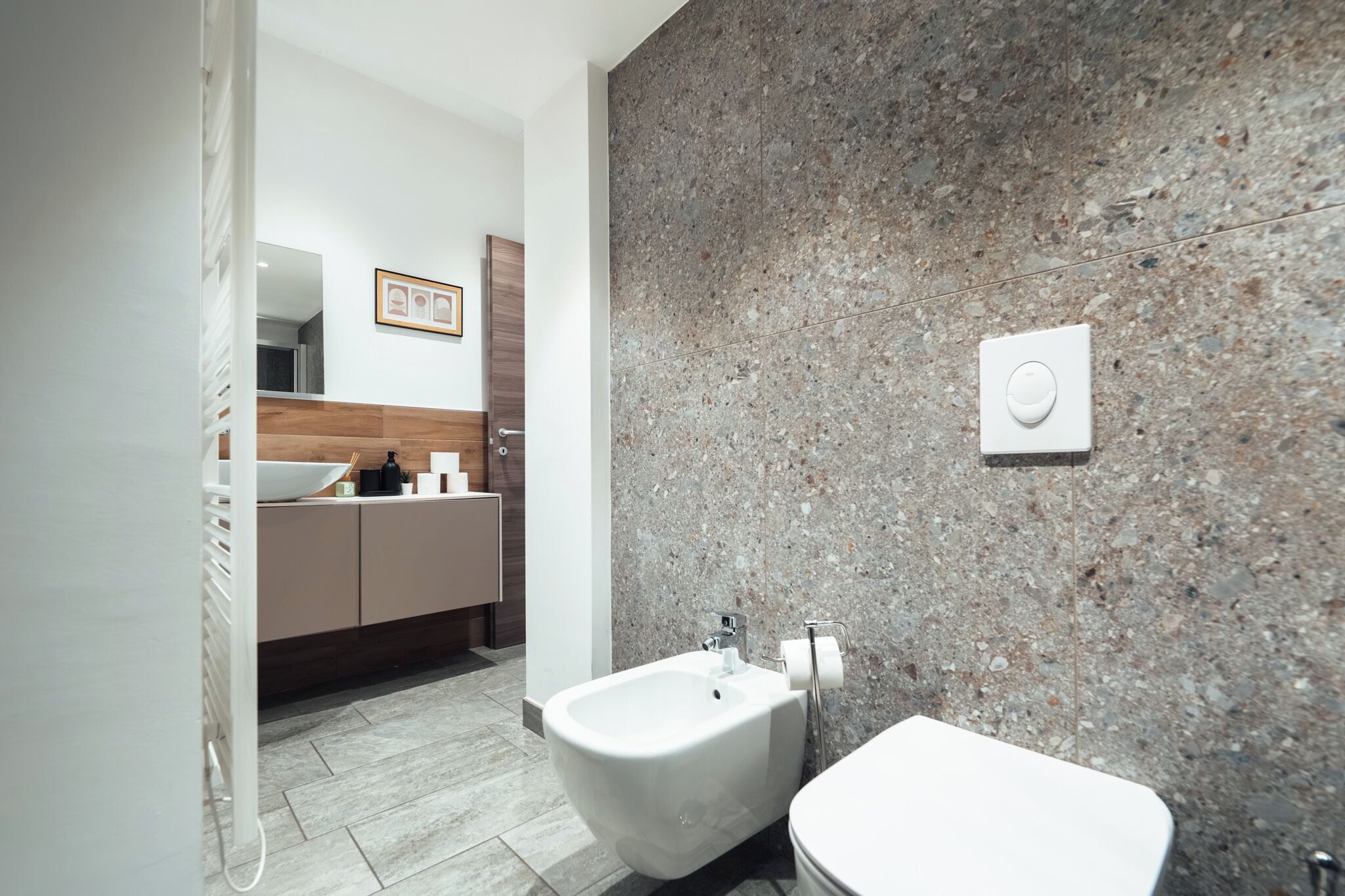 Un bagno moderno con bidet, water e parete in granito.