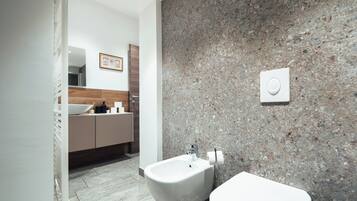 Un bagno moderno con bidet, water e parete in granito.