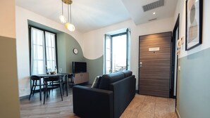 Un salon moderne avec un canapé, une table à manger, un téléviseur et de grandes fenêtres.