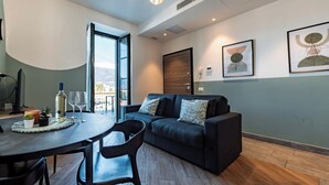A modern living room with a sofa, a dining table with chairs, a large window, and artwork on the walls. - Ciclamino - Modern apartment with private parking. Lake view (Bellano)